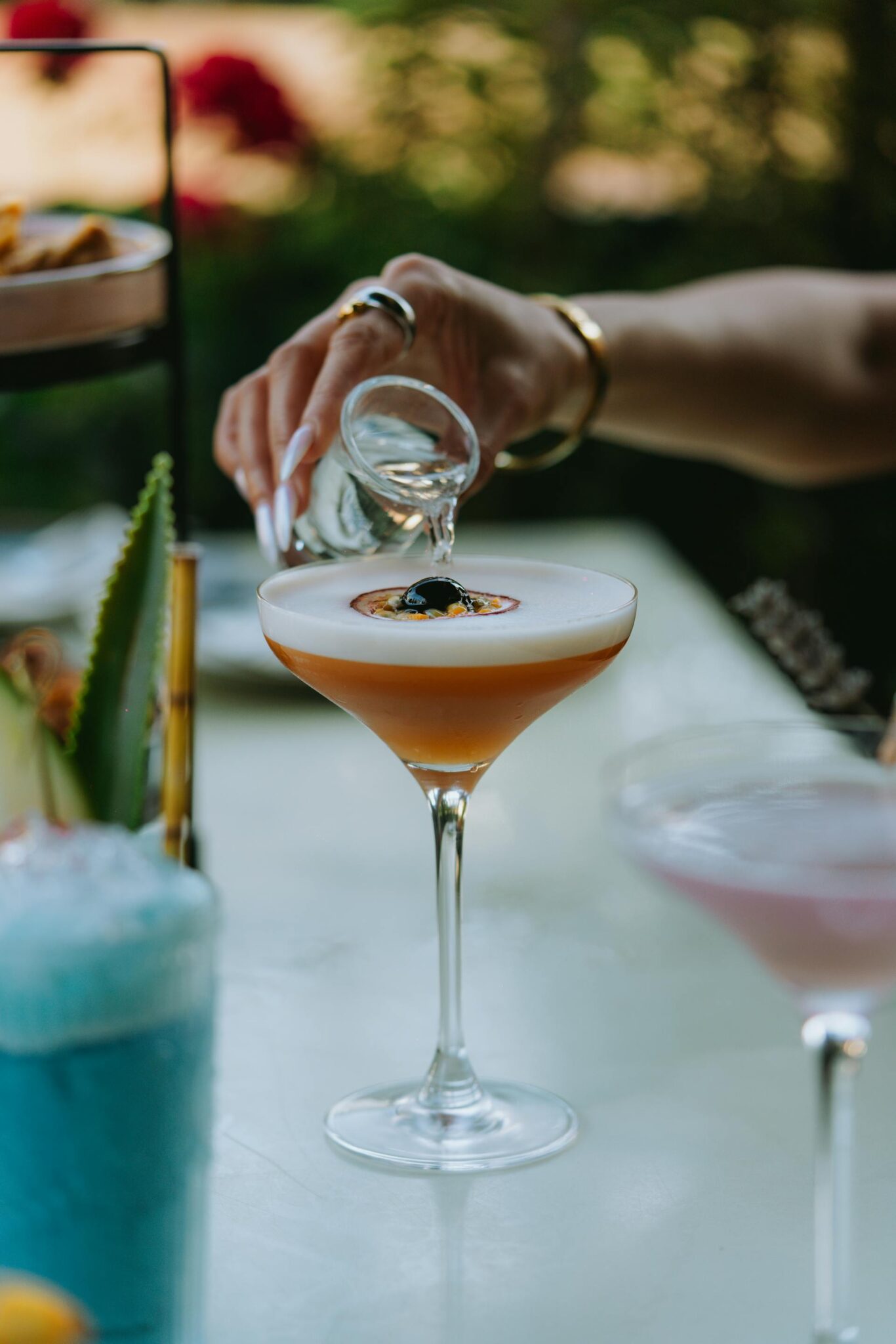 Profesionalus barmenas ruošiantis spalvingus kokteilius prie stilingo mobilaus baro vestuvių šventėje.